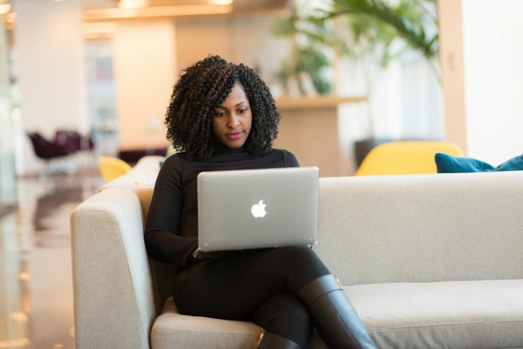 Woman Using Macbook Sitting on White Couch